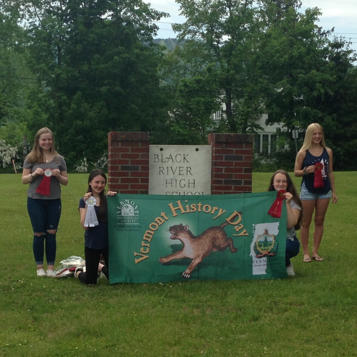 Four students holding Vermont History Day banner